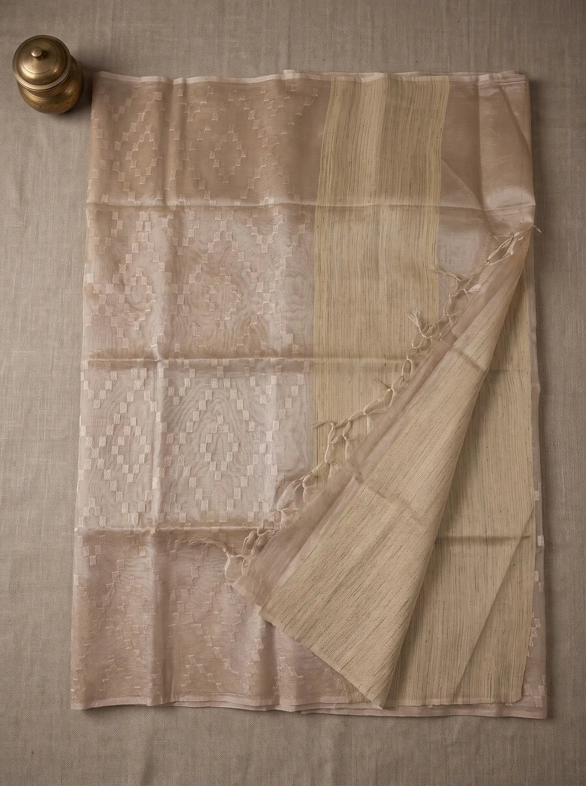 Linen-colour kota tissue saree displayed flat with geometric zari embroidery, striped pallu and tasselled edge