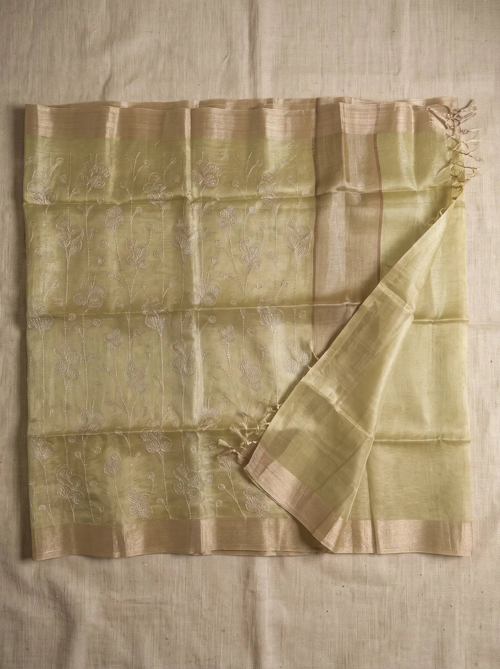 Pista green kota tissue saree displayed flat with floral zari embroidery, contrasting border and tassled pallu